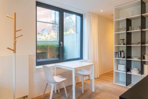 einen weißen Tisch und Stühle in einem Zimmer mit Fenster in der Unterkunft Strandlust 21A Appartement in Wittdün