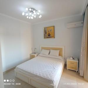 a bedroom with a white bed and a chandelier at Private 3 bdrm apartment at ElKarma Aqua Beach Reaort in Hurghada +25 photos