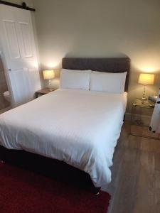 1 dormitorio con 1 cama grande con sábanas y almohadas blancas en Joan B+B en Clonakilty