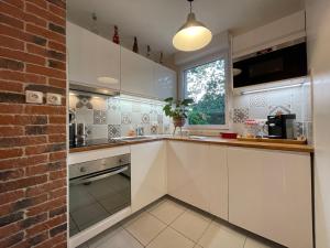 a kitchen with white cabinets and a brick wall at Manoir by Yumē in Toulouse