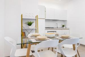 een eetkamer met een glazen tafel en witte stoelen bij Loft Salgari in Turijn