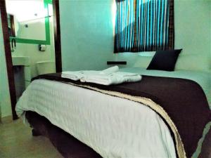 Una cama con toallas blancas encima. en Green House Araque Inn, en Otavalo
