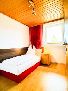 Schlafzimmer mit einem Bett mit einem roten Vorhang und einem Fenster in der Unterkunft Ferienhaus Am Hofacker in Aflenz Kurort