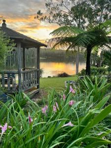 a gazebo next to a lake with flowers at The Lake House in Yungaburra