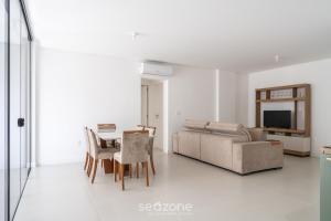 ein Wohnzimmer mit einem Sofa, einem Tisch und Stühlen in der Unterkunft Apto confortável a 5 min da praia ROT1001 in Itapema