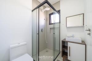 ein Bad mit einer Glasdusche und einem Waschbecken in der Unterkunft Apto confortável a 5 min da praia ROT1001 in Itapema