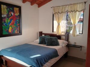 - une chambre avec un lit doté de draps bleus et une fenêtre dans l'établissement Finca con vista al embalse y jacuzzi, à Guatapé