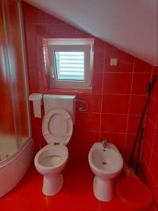 a red bathroom with a toilet and a sink at Apartmani Vesna in Pag