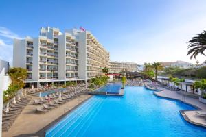une piscine avec des chaises longues et un hôtel dans l'établissement Alexandre Hotel Troya, à Playa de las Americas