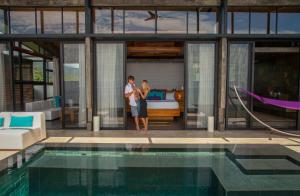 a man and a woman standing next to a swimming pool at Kura Boutique Hotel Member of the Cayuga Collection in Uvita