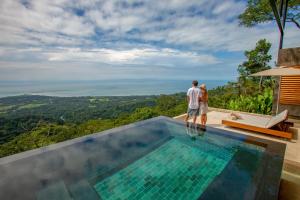 a man and woman standing on the edge of a swimming pool at Kura Boutique Hotel Member of the Cayuga Collection in Uvita