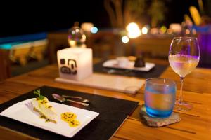 a table with a plate of food and a glass of wine at Kura Boutique Hotel Member of the Cayuga Collection in Uvita