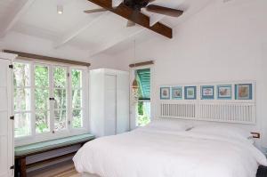 um quarto branco com uma cama grande e janelas em Hotel Aguas Claras Member of the Cayuga Collection em Puerto Viejo