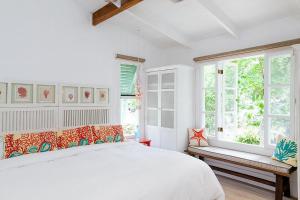 a white bedroom with a bed and a window at Hotel Aguas Claras Member of the Cayuga Collection in Puerto Viejo