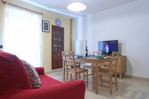 sala de estar con mesa, sillas y TV en Casa Vacanza Nì Rosa, en Cefalú