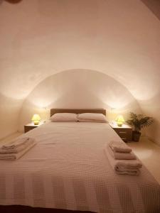 a bedroom with a large white bed with two lamps at Corte Perugia in Matino
