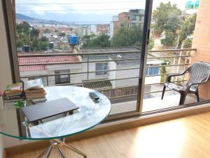een glazen tafel en een stoel voor een groot raam bij Hermoso, Apacible - Apartamento Central - Tunja in Tunja
