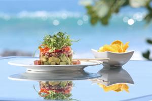 a tray with two plates of food on top at Arenas Del Mar Beachfront & Rainforest Resort Member of the Cayuga Collection in Manuel Antonio