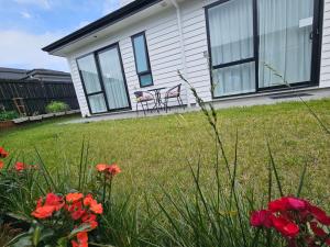 a house with red flowers in the yard at Tui Nest Garden Unit in Silverdale