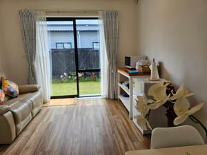 a living room with a couch and a sliding glass door at Tui Nest Garden Unit in Silverdale