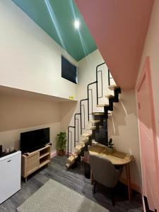 a room with a staircase with a table and a tv at Cozy En-suite Loft in Trendy Local in London