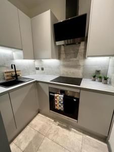 cocina con armarios blancos, fregadero y horno en 1 bed Apt in West End en Glasgow