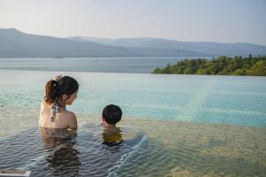 Una mujer y un niño parados en el agua en New Akan Hotel, en Akankohan