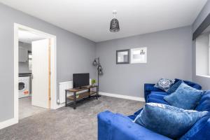 a living room with a blue couch and a tv at M1 M62 Lofthouse, Wakefield - Off Road Parking, Self Check-in, Wi-Fi, En-suite & Smart TV in Every Bedroom - Families, Contractors, Long Stays in Wakefield
