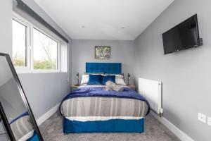 a bedroom with a blue bed and a flat screen tv at M1 M62 Lofthouse, Wakefield - Off Road Parking, Self Check-in, Wi-Fi, En-suite & Smart TV in Every Bedroom - Families, Contractors, Long Stays in Wakefield