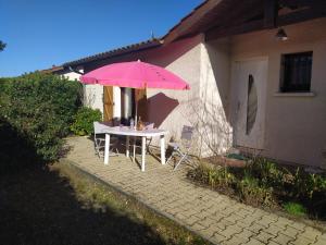 a table with a pink umbrella in front of a house at Villa Nancea Bassin Arcachon Gujan Mestras in Gujan-Mestras