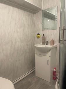 uma casa de banho branca com um lavatório e um espelho em 2 Bedroom Apartment on suite bathroom, Southmead Bristol em Bristol