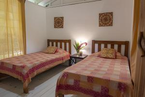a bedroom with two beds and a table with a vase of flowers at Vishraam House ~ A pocos pasos de la playa in Cocles