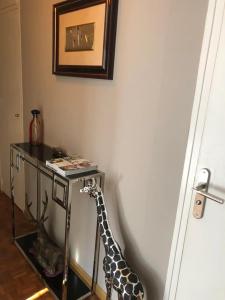 une girafe debout à côté d'une table dans une pièce dans l'établissement Chambre Privée avec salon Châtillon près de Paris, à Châtillon