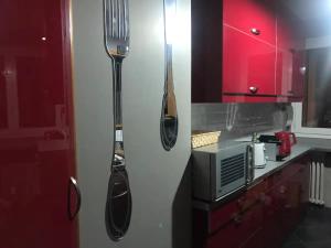 een keuken met rode kasten en keukengerei aan de muur bij Chambre Privée avec salon Châtillon près de Paris in Châtillon