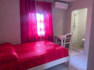 a bedroom with a red bed and a shower at Location chambres chez Zam in Mamoudzou