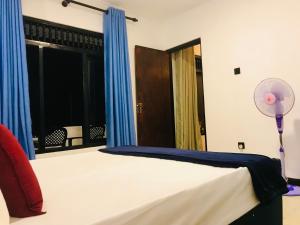 a bedroom with a bed with blue curtains and a fan at Cloud Nine in Kandy