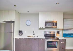 una cocina con armarios blancos y electrodomésticos de acero inoxidable en Luxury Boutique 2 Bedroom Condo - 1B, en Niagara Falls