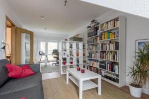 uma sala de estar com um sofá e uma prateleira cheia de livros em Private Rooms em Hanôver