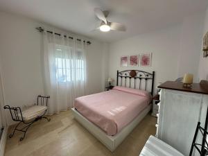 ein Schlafzimmer mit einem Bett und einem Stuhl und einem Fenster in der Unterkunft Adosado en Novo Atlantico Golf in Novo Sancti Petri