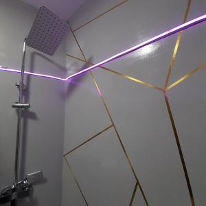 a shower with a neon light on a wall at Pannónia Rooms and Apartments in Satu Mare