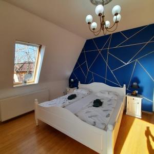 a bedroom with a white bed and a blue wall at Pannónia Rooms and Apartments in Satu Mare