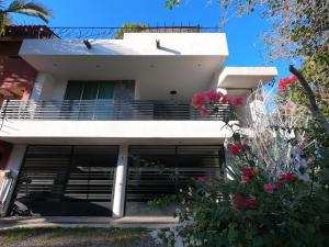 a white house with some flowers in front of it at Casa Arbol de Paz Hab Sencilla in Chacala +17 photos