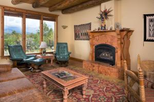 a living room with a fireplace and green chairs at Blue Lake Ranch in Hesperus