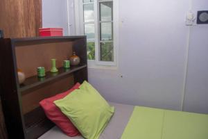 a bed with a colorful pillow and a window at The Biltons - 6 min from airport- A/C in all rooms in Montego Bay