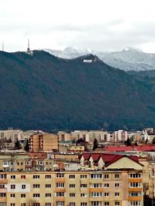 eine Stadt mit Gebäuden und einem Berg im Hintergrund in der Unterkunft Penthouse City View Infinity in Braşov