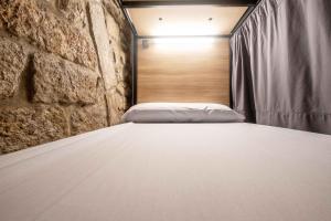 Bett in einem Zimmer mit Ziegelwand in der Unterkunft Albergue Santiago de Caminha in Caminha