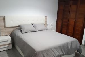 een slaapkamer met een wit bed en een houten kast bij Apartamento con amplia terraza en Candelaria in Candelaria