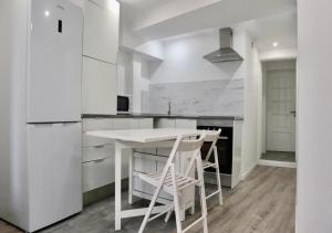 a white kitchen with a white table and chairs at Matching Loures Guest House in Loures