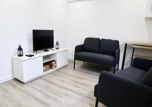 a living room with two chairs and a flat screen tv at Matching Loures Guest House in Loures