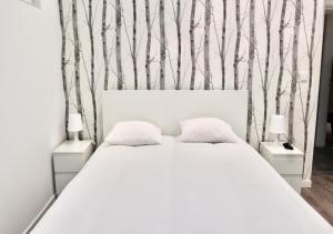Un dormitorio con una cama blanca con árboles en la pared en Matching Loures Guest House en Loures
